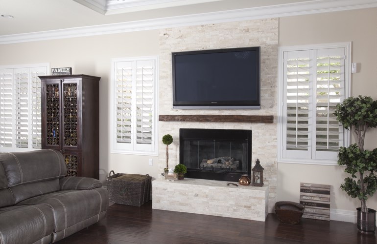 White plantation shutters in a Dover living room with dark hardwood floors.